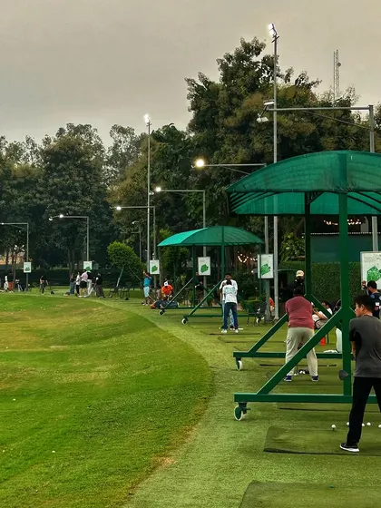 The driving range under the evening lights, with numerous bays occupied. It's a popular spot for unwinding after work or for a weekend night out.