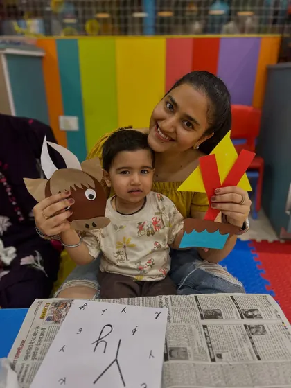 A mother and child at our Rajouri Garden center proudly show off their finished paper crafts, including a yak and the letter 'Y'. We often link our crafts to alphabet learning.
