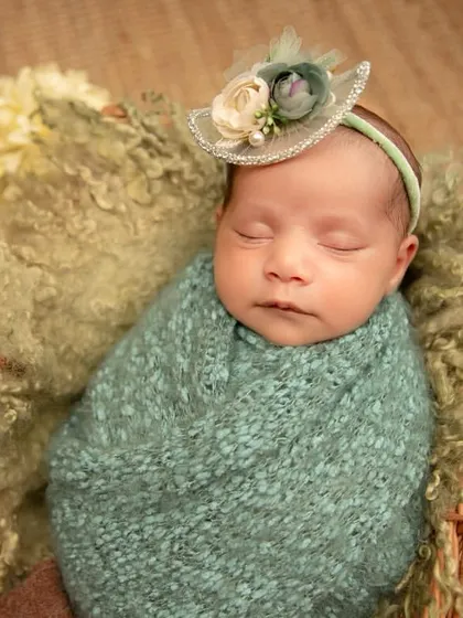 A detailed shot of a newborn wearing a tiny, elegant hat. Her peaceful expression and the intricate details of the prop make this a beautiful portrait.