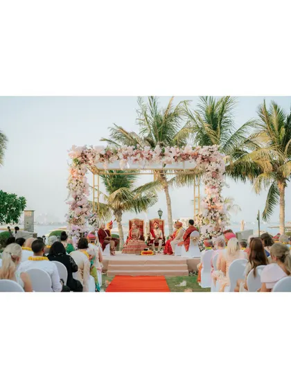 A wide shot of the beach wedding ceremony in progress, capturing the couple, the guests, and the stunning ocean backdrop.