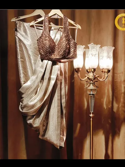 Elegance in every step. This shimmering gold drape saree with a halter neck blouse is laid out to showcase its beautiful fabric and intricate design.