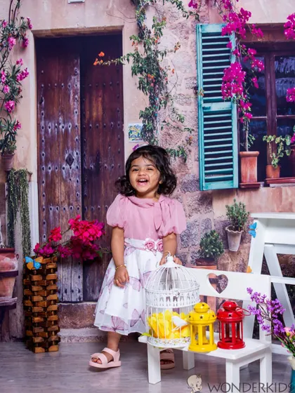 A toddler's pure happiness captured in a photo. Her joyful laugh and the charming European street backdrop create a lively and beautiful portrait.