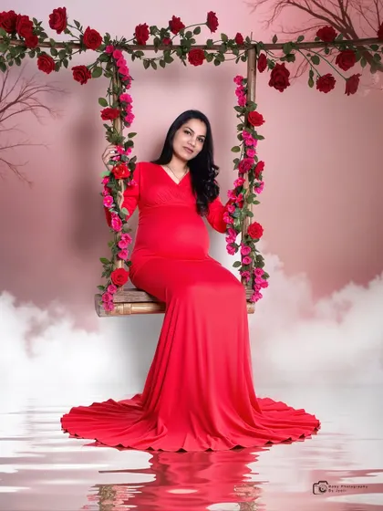 A creative studio portrait on a floral swing with a pink sky backdrop and a water reflection, creating a fantasy-like atmosphere.