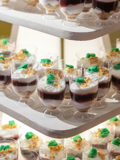 A multi-tiered display of our dessert shooters. The layers of chocolate, cream, and green crumble create a visually interesting and delicious single-serving dessert.