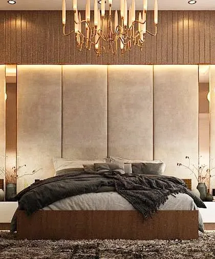 This master bedroom is a study in sophisticated comfort. The design features a tall, upholstered headboard flanked by wood paneling and integrated mirrors, with soft lighting from a modern chandelier and bedside pendants.