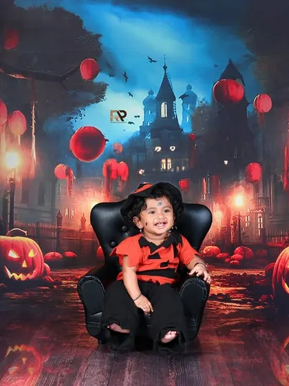 A smiling baby sits in a chair, ready for some Halloween fun. The jack-o'-lanterns and haunted street backdrop create a perfectly spooky and adorable scene.