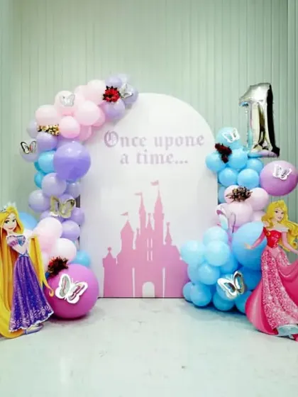 A classic Disney Princess first birthday party. This setup includes life-sized cutouts of Ariel, Rapunzel, Aurora, and Snow White against a castle-themed backdrop.