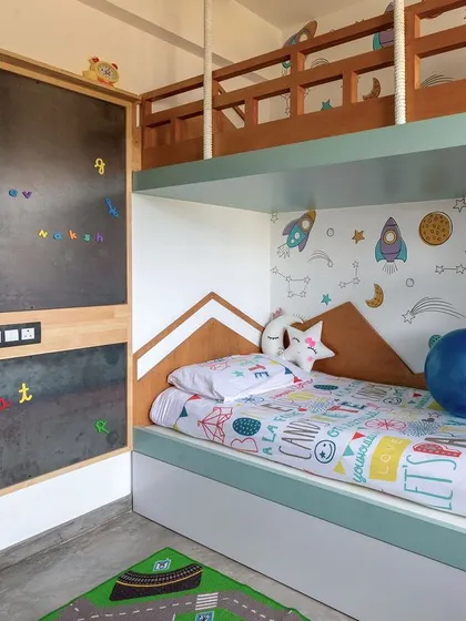 The room includes a space-themed wallpaper and a magnetic chalkboard wall, encouraging imagination and fun.