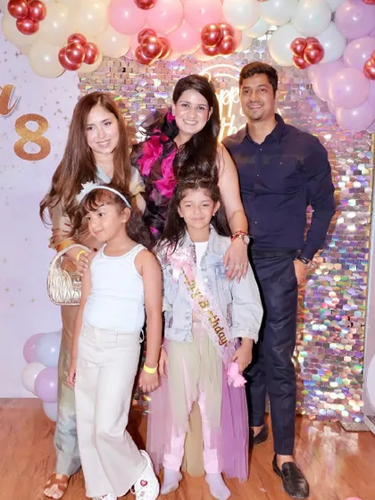 A family poses for a group photo at a unicorn-themed birthday party.