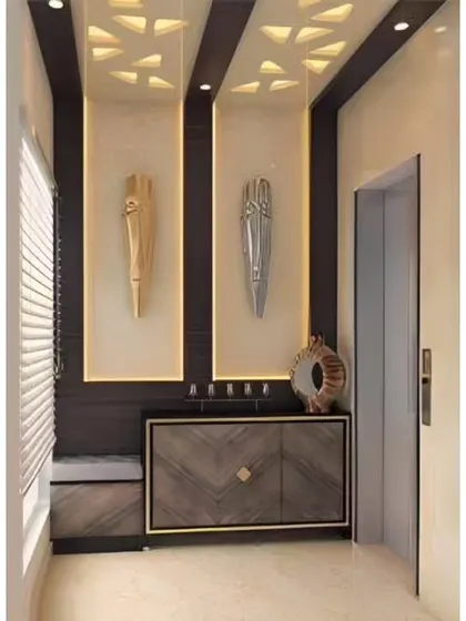 A luxurious entryway design featuring backlit wall panels with African mask art. The chevron-patterned cabinet and false ceiling with cutouts add layers of sophistication.