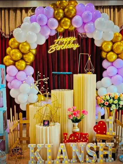 A sweet birthday setup for Kiansh, with lavender, white, and gold balloons, 'BABY' blocks, and a picket fence.