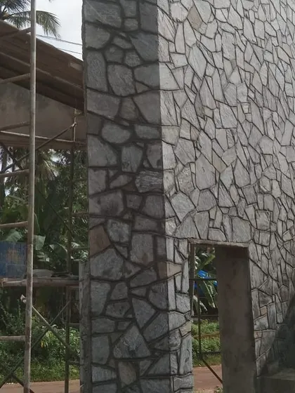 An exterior wall and gateway being covered with random-sized stone cladding.