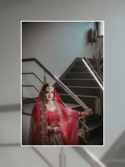 A portrait of Shreya on a staircase, her red lehenga flowing, creating a classic and elegant composition.