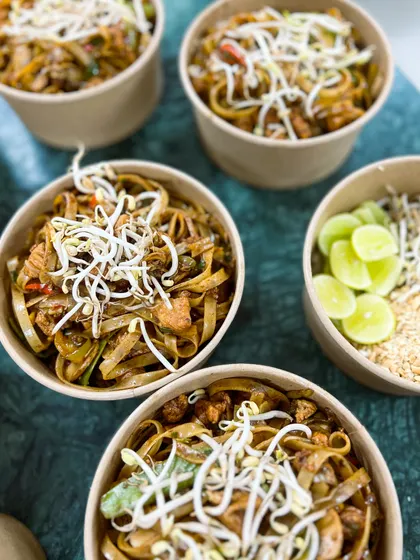 Our Pad Thai noodles, topped with fresh bean sprouts and lime wedges. We pack the crushed peanuts separately to keep them crunchy.