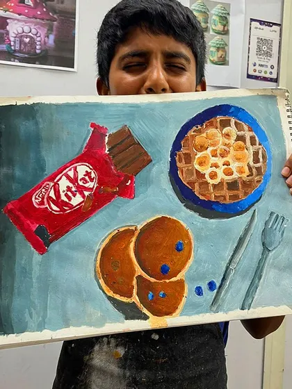 This student is happy with his finished piece, a playful composition of his favorite snacks that demonstrates a solid grasp of acrylic painting fundamentals.