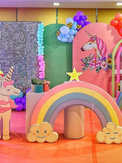 A modern and colorful unicorn party setup with a silver sequin wall, a rainbow prop, and a large unicorn cutout.