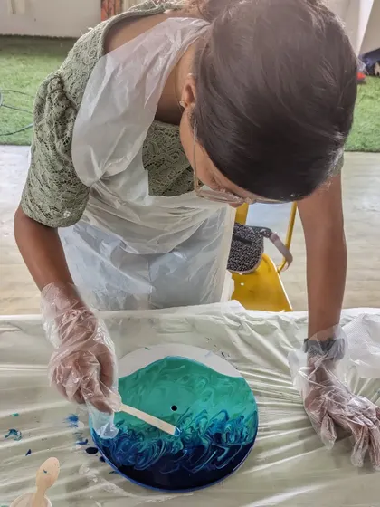 A participant carefully creating lacing effects with a stick to form waves in her resin beach art. We guide you through specific techniques to achieve stunning, realistic results.
