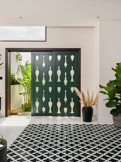 This wide shot shows the full expanse of the home spa, from the freestanding tub to the custom door and inlay wall panel. The black and white floor tiles ground the space and provide a graphic contrast to the organic forms of the plants and artwork.