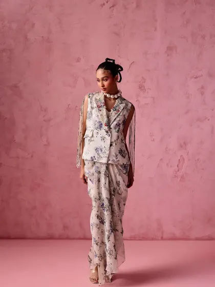 A modern take on the saree. This look features a floral print draped skirt paired with a sleeveless blazer, offering a chic and powerful fusion style for a contemporary wedding guest.