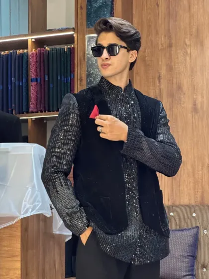 Another look at the all-black sequined kurta with a velvet waistcoat. The red pocket square adds a pop of color to this dark, sophisticated ensemble.