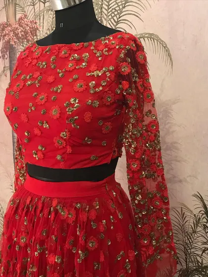 A close-up of the blouse from our red net lehenga, showing the delicate floral embroidery that covers the full sleeves and bodice.