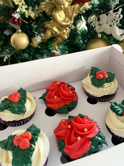 A box of my signature cupcakes decorated for the holidays. The red poinsettias and white holly designs bring the Christmas spirit to life.