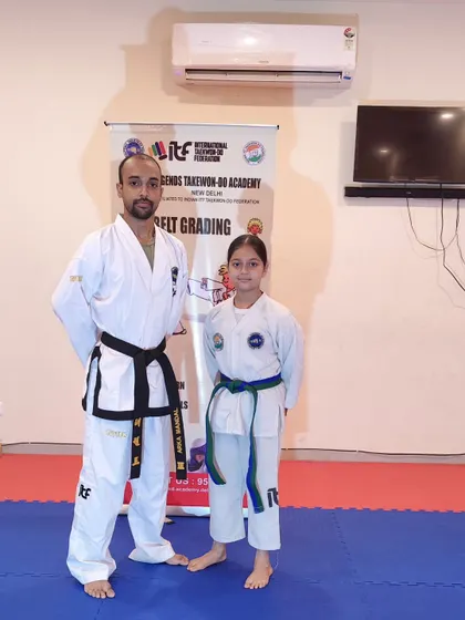 A young female student poses with her coach after her promotion, a proud moment for both.