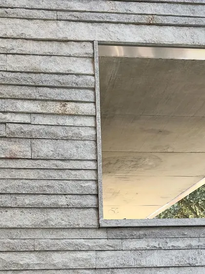 A detail of a window opening set within a wall of stacked, rough-hewn stone. This work-in-progress shot highlights our focus on the junction between different materials and the creation of clean, simple geometries.