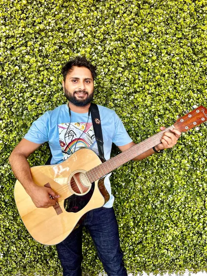 Posing with my guitar against a green wall. A simple, happy shot that captures my love for music.