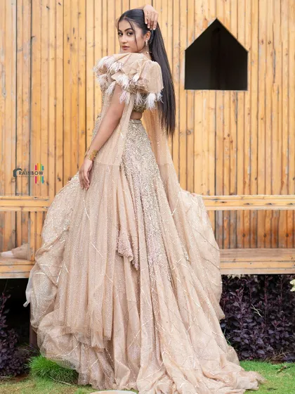 A full-length shot of a model in a dramatic beige gown, showing off the outfit's volume and texture.