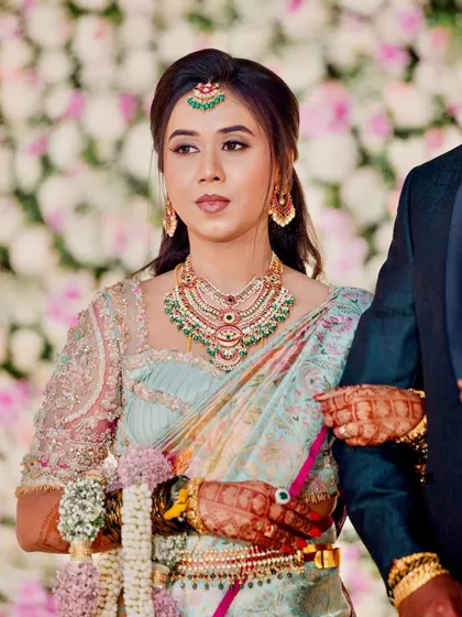 A beautiful portrait of the bride at her reception. The pastel colors of her saree and the intricate embroidery on her blouse create a look of modern elegance.