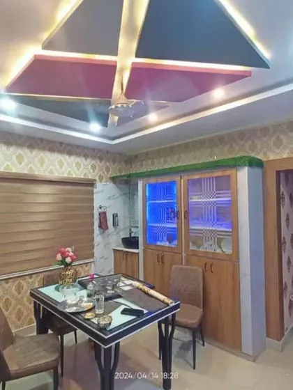 This dining area showcases a classic damask wallpaper that adds elegance and a traditional touch. The wallpaper complements the room's unique ceiling design and wooden furniture.
