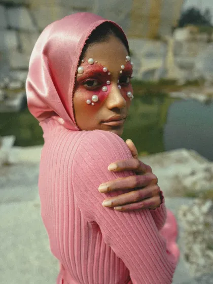 A close-up portrait from the 'MAGENTA' editorial. The concept was built around a single, dramatic color, with pearl-adorned makeup and a satin headscarf adding texture and a futuristic feel against the stark quarry background.