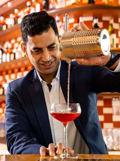 Another shot of our Head of Bars, Varun Sharma, pouring a vibrant red cocktail.