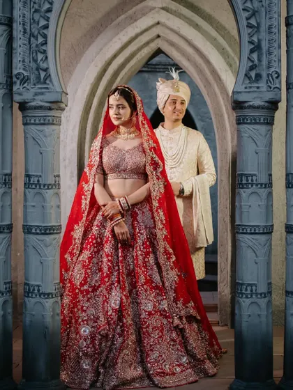 A stunning portrait of the bride and groom, framed by the grand, arched architecture of their wedding venue.