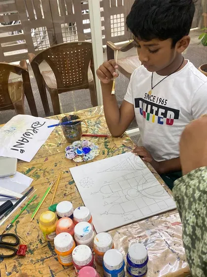 A student carefully sketches his design before painting, learning the importance of planning in art.
