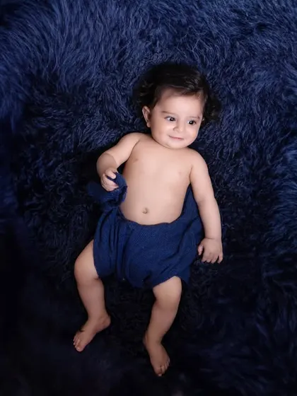 A minimalist portrait focusing on the baby's sweet expression. The simple setup with a deep blue, fluffy rug creates a beautiful contrast and keeps the focus on the child.