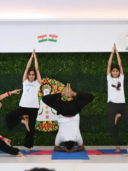A dynamic group pose featuring a central headstand supported by surrounding practitioners. This represents the balance, strength, and interconnectedness we cultivate in our community.