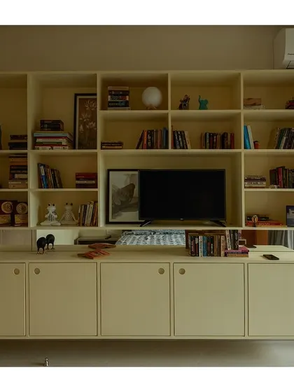 A custom-built shelving unit provides ample storage for books and media while maintaining a light and airy feel.