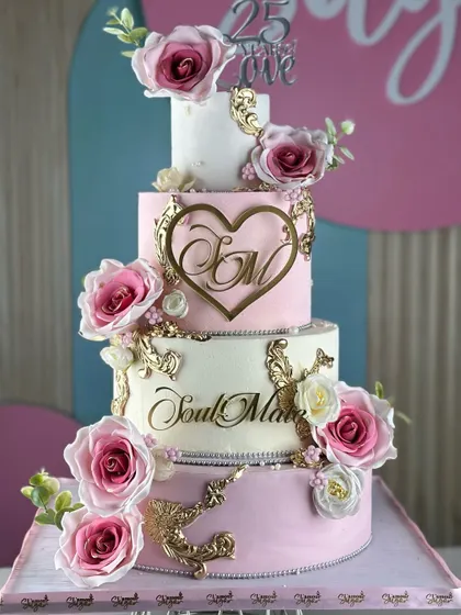 A love story in every layer. This white and pink tiered cake is a classic, featuring delicate gold accents, personalized monograms, and beautiful pink sugar roses for a truly romantic celebration.