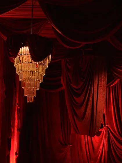 A close up of a tiered crystal chandelier, elegantly draped with red velvet. This detail shot shows how we combine elements to create a cohesive and luxurious event design.