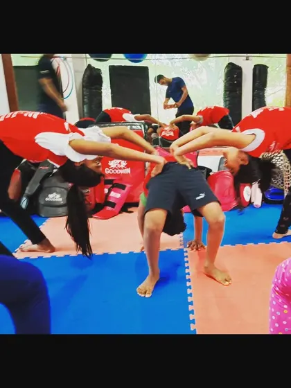 A group of students practicing their bridge pose together. Working in a group helps them motivate each other and perfect their form for better back flexibility.
