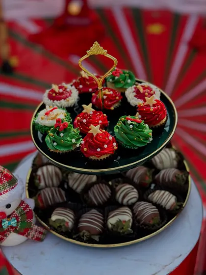 Holiday sweetness served in style. A two-tiered stand showcasing our festive cupcakes and chocolate-dipped strawberries for a Christmas party.