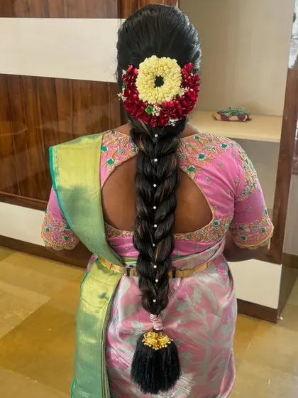 A traditional braid with pearl accents woven through, finished with a gajra of jasmine and red flowers.