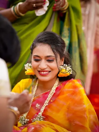 A beautiful, smiling bride during her Haldi ceremony. The floral jewelry and the warm, happy colors make this a joyful and vibrant portrait.