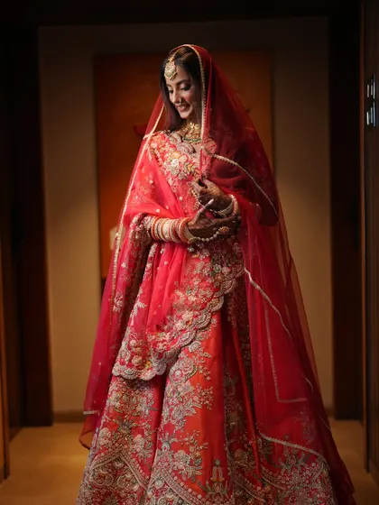 Bridal beauty that turns heads and steals hearts. This bride is glowing in her red-orange lehenga, with soft, natural-looking makeup that enhances her features.