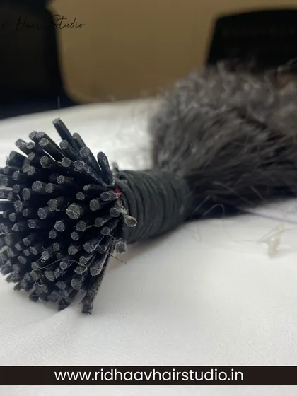 This shot highlights the individual I-tips on our raw curly extensions. These are ready for a professional, strand-by-strand application to create a full and dynamic curly hairstyle.