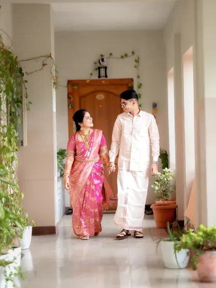 A candid moment of the couple walking hand-in-hand down a plant-lined corridor after their ceremony.