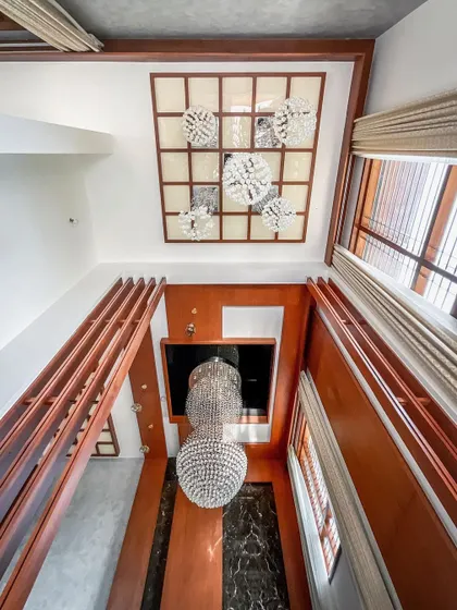 A view looking up at the multi-level ceiling design. The composition includes a coffered wood ceiling, a cluster of modern light fixtures, and the reflection of the main chandelier, showcasing our attention to every surface.