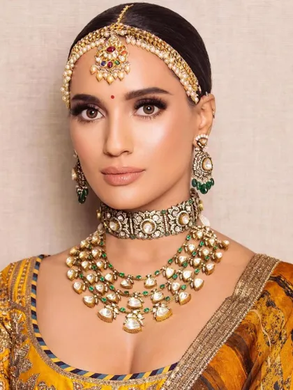 A traditional Haldi look with a yellow outfit and floral jewelry. The makeup is kept minimal and fresh, with a focus on waterproof products that can withstand the festivities.